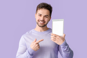 Canvas Print - Young man with tablet computer on color background