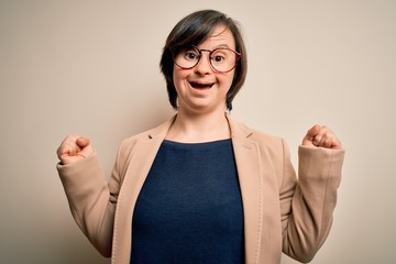 Poster - Young down syndrome business woman wearing glasses standing over isolated background celebrating surprised and amazed for success with arms raised and open eyes. Winner concept.