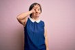 © Krakenimages.com - Young down syndrome woman wearing elegant shirt over pink background doing ok gesture with hand smiling, eye looking through fingers with happy face.