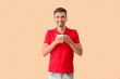 © Pixel-Shot - Young man with cup of hot coffee on color background