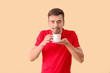 © Pixel-Shot - Young man with cup of hot coffee on color background