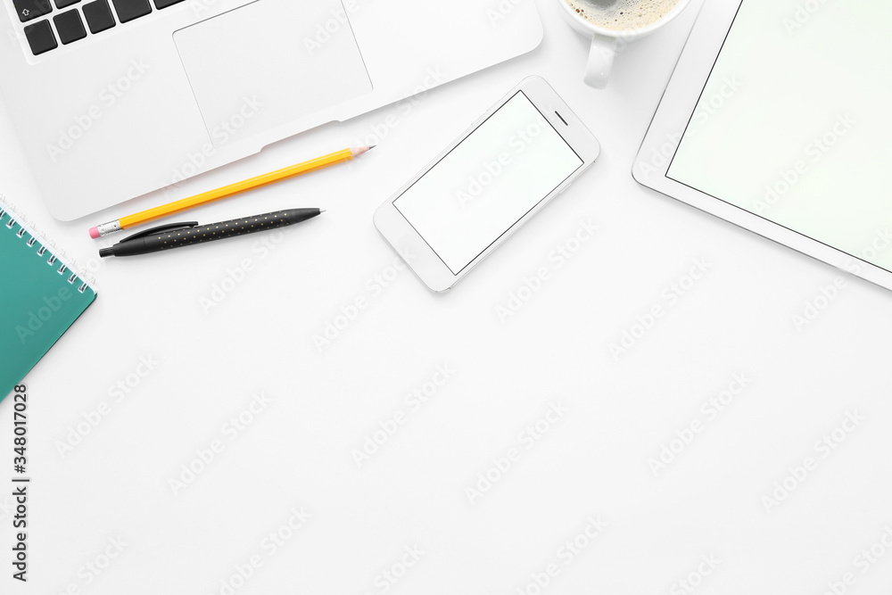 Tablet computer, mobile phone, laptop and stationery on white background