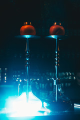 Two grapefruit shishas on a bar counter of night club, with bulbs enlightened with blue neon light