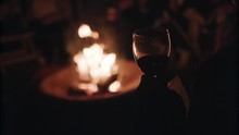 A Woman Holds A Glass Of Wine By A Beach Campfire.
