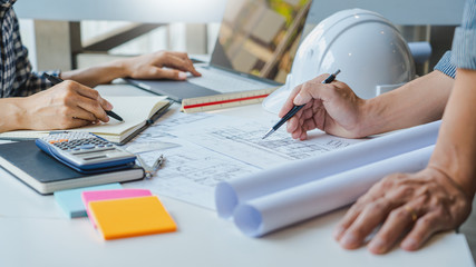 Wall Mural - engineer Hand Drawing Plan On Blue Print with architect equipment discussing the floor plans over blueprint architectural plans at table in a modern office.