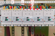 The number of high-power electric circuit breakers molded case circuit breakers in an electrical closet. Electrical cables or wires are connected to the switches. The cables are marked with color.