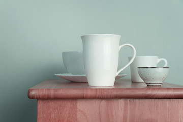 white ceramic coffee and tea cup and dish set for food and drink on wood table with interior vintage blue background