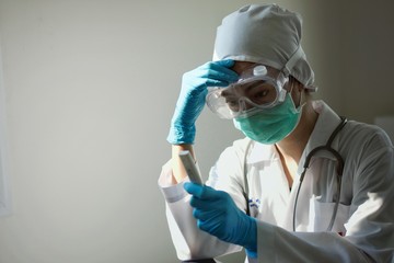 Close up of  female asian  doctor is infected with a virus  has stress in Coronavirus outbreak or Covid-19, in wearing protective shuit, Green mask,face shield and blue gloves 