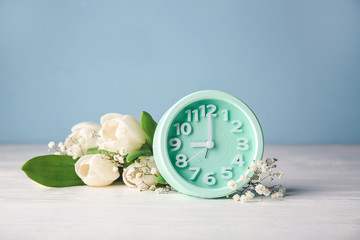 Alarm clock and flowers on table. Spring time