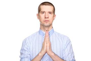 Wall Mural - serious focused man in a classic blue shirt, short haircut; holds his hands in prayer. Isolated