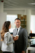 © JustLife - Colleagues in office. Businesswoman and businessman discussing work and drinking coffe in office