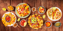 Mexican Food Panorama, Shot From The Top On A Dark Rustic Wooden Background. Nachos, Guacamole, Tequila, Tacos, A Flat Lay