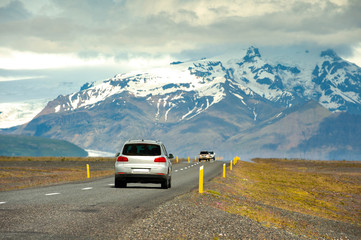 Sticker - The car is running on the highway. In the countryside in Iceland The background is a great and exciting mountain. Road trip concepts and driving in traveling.