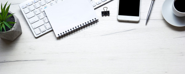 White desk office with laptop, smartphone and other work supplies with cup of coffee. Top view with copy space for input the text. Designer workspace on desk table essential elements on flat lay