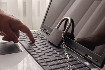 The laptop on which there is a lock with a chain. Finger clicks on the keyboard.