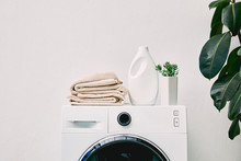 Detergent Bottle And Towels On Washing Machine And Green Plant In Bathroom