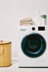 Wall Mural - green plant, detergent bottle and towels on washing machine near laundry basket in bathroom