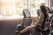 Woman adjust workout intensity monitor of recumbent bike