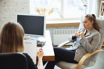 Wall Mural - Young woman sitting in office during the job interview with female employee, boss or HR-manager, talking, thinking, looks confident. Concept of work, getting job, business, finance, communication.