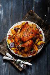 Roast whole chicken with roast vegetables on plate on a table