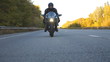 Motorcyclist racing his motorcycle on country road. Young man in helmet riding fast on modern sport motorbike at highway. Guy driving bike during trip. Concept of adventure. Front view Close up