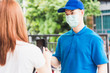 © sorapop - Asian delivery express courier young man giving parcel boxes to woman customer signature for receiving on mobile phone both protective face mask, under curfew quarantine pandemic coronavirus COVID-19