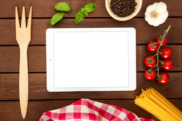 White tablet with copy space on a wooden background with ingredients for cooking Italian pasta