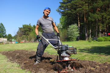 Man plows ground with motor cultivator.