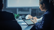 © Gorodenkoff - In the Corporate Meeting Room: Young Business Associate Sits at the Conference Table and Uses Digital Tablet Computer, She is Surround by Businesspeople's Silhouettes.