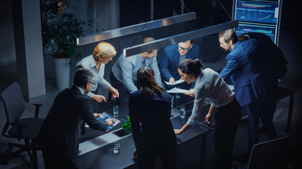 Leinwandbilder - In the Dark Corporate Meeting Room Diverse Group of Executives, Business Associates and Investors Lean on a Conference Table During Emotional Discussion, Planning and Strategizing. High Angle Shot