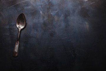 Old shabby spoon on a metal background. Background for the menu at the loft-style, top view.