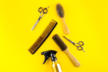 Wall Mural - Hairdressing instruments. Combs, scissors and spray on yellow desk from above frame space for text