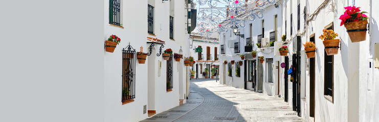 Sticker - Panoramic image white copy space view, empty street famous village of Mijas in Spain. Charming narrow streets with New Year decorations, hanging flower pots on walls, no people. Costa del Sol, Malaga