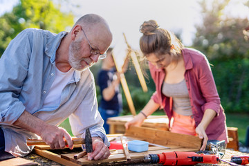 A man and his family are building wooden planters for their vegetable garden