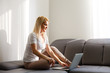 © Angelov - Woman using a laptop while relaxing on the couch