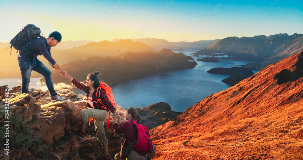 Young asian three hikers climbing up on the peak of mountain. People helping each other hike up a mountain at sunlight. Giving a helping hand. Climbing. Helps and team work concept
 - obrazy, fototapety, plakaty 
