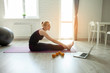 © Богдан Маліцький - Sport at home. girl watches an online tutorial on a laptop and does an exercise on flexibility in a room, an athlete doing yoga on self-isolation