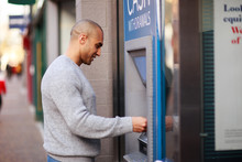 A Young Man Withdrawing Cash From A Cash Point.
