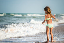 Rear View Of A Little Four Year Old Girl Swimming In The Sea On A Warm Summer Day During Summer Vacation In A Tropical Country. Concept Vacation With Children.