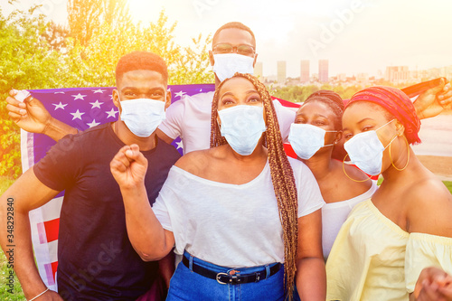 Group of girls and boys in medical mask smiling with American flag in spring park autumn evening learning English language exchange students