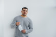 © Andrii - A young man stands on a gray background wearing a mask during a quarantine with free space. Quarantine in the mask