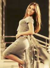 Happy Young Fashion Woman In Gray Crop Top And Skirt Suit Leaning On Railing