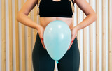 Fototapeta  - Close up of a young woman holding a balloon to explain the diaphragm zones, core and pelvic floor. Pelvic floor exercises explained