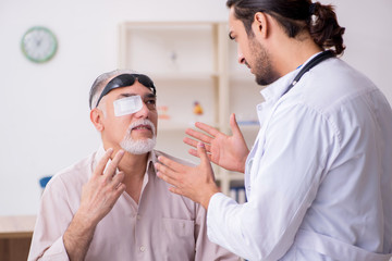 Wall Mural - Old blind man visiting young male doctor