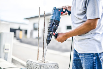 Man worker with pneumatic hammer or drill perforator equipment making hole in bricks wall at construction.