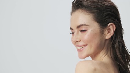 Poster - A charming young half-naked woman with wet hair is posing and winking while turning her head to the camera isolated over a light blue background in studio