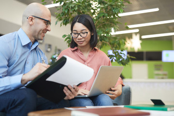 Wall Mural - Portrait of young Asian businesswoman talking to manager while working on internship project, copy space