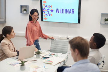 Wall Mural - portrait of young asian woman smiling cheerfully while giving presentation during business seminar o