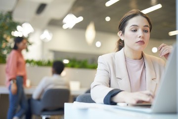 Wall Mural - Portrait of young businesswoman using laptop while working in cafe, copy space