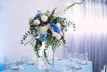 The Festive Table Is Decorated With A Vase Of Flowers, Table Decor With A Gardenia, A Wedding Celebration, A Blue Tablecloth, There Are Chairs, Table Setting, Dinner With Guests In A Restaurant